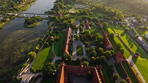 Drohne fliegt zurück über Schloss Malbork und zeigt Sonnenaufgang in der polnischen Landschaft
