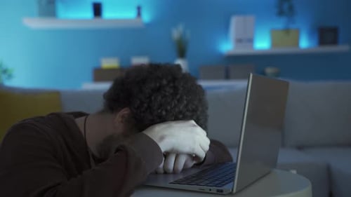 Tired Man Working Late on Laptop at Home
