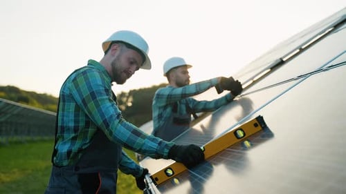 Zwei Ingenieure installieren Sonnenkollektoren in einem nachhaltigen Kraftwerk