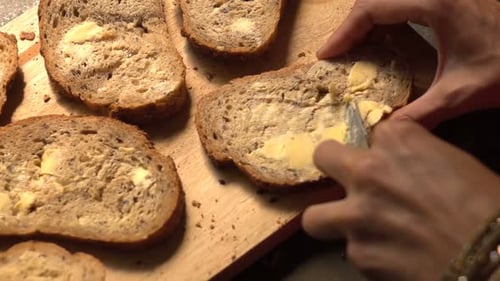 Buttering multigrain bread slices on wooden cutting board