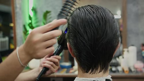 Hair Stylist Using Dryer and Comb in Salon