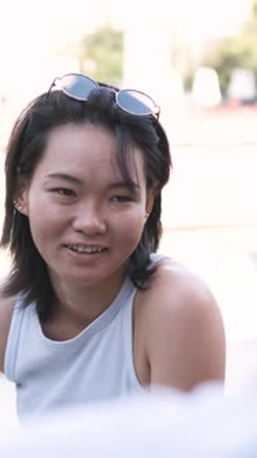Happy Woman Listening to Man Talking at City Park During Sunny Day