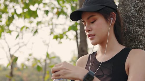 Asian women after run. female drinking water from bottle after workout