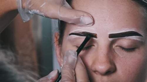Woman Receiving Eyebrow Treatment at a Beauty Salon