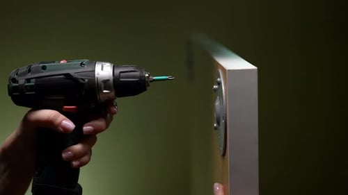 Woman Attaches Metal Bracket with Electric Screwdriver