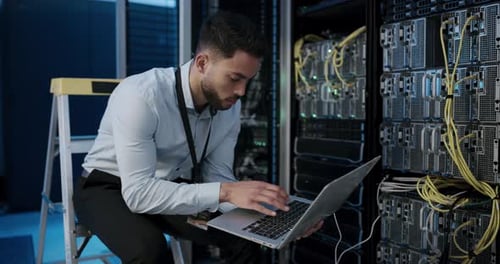 Young Adult Working on Laptop in Server Room