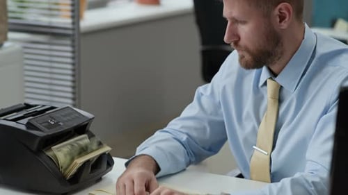Employee Counting Banknotes in Electronic Device Talking to Colleague in Bank