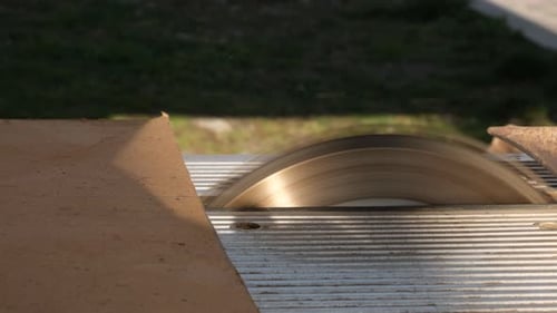 Thin Hardboard Sheet Approaches Spinning Circular Saw Blade and Begins to Be Cut By Sharp Teeth