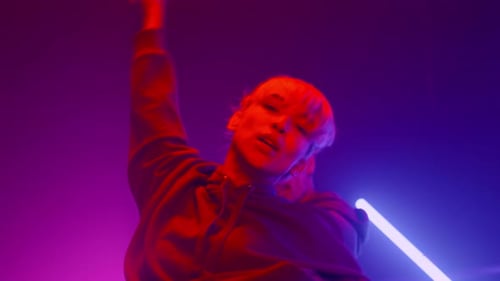Stylish young adults dancing in vibrant neon lighting