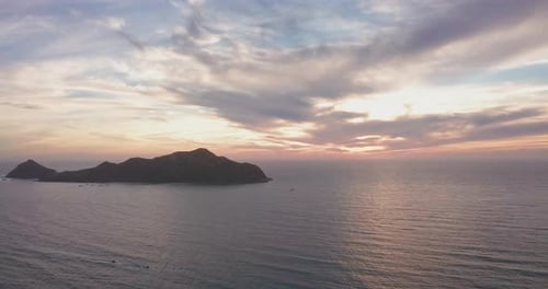 Jib up of small island in ocean at sunset