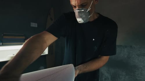 Surf board factory. Adult male shaper creates the surfing board on the factory