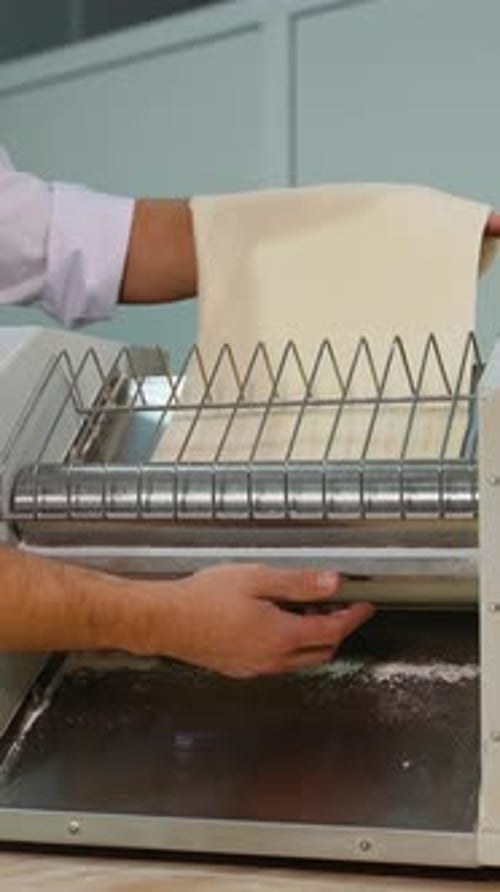 Koch füttert Teig in die Teigwalzmaschine