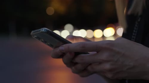 Woman Uses Smartphone on Night Street