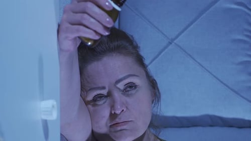 Worried Woman Lying in Bed with Pills at Night