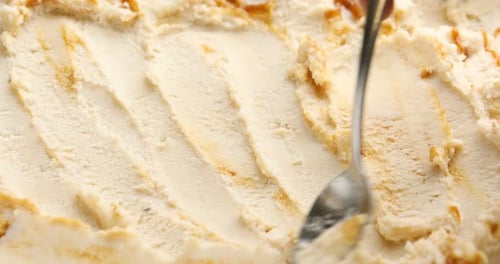 Spreading tasty vanilla ice cream with spoon, closeup