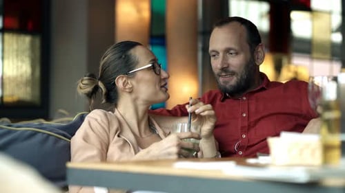 Happy Couple Talking And Drinking Juice In Cafe