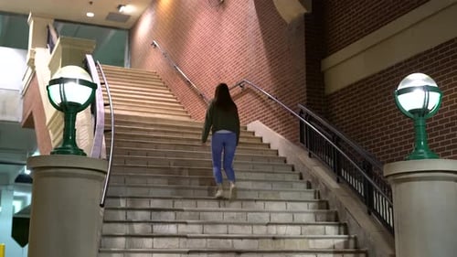 4K footage of woman walking up steps towards a building.