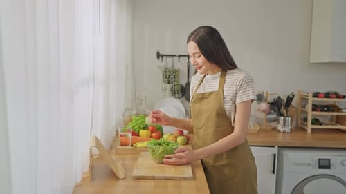 Portrait of Asian woman cooking green healthy salad in kitchen at home.