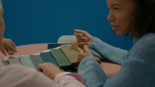 Two Fashion Designers Discussing Over Fabric Samples in Office