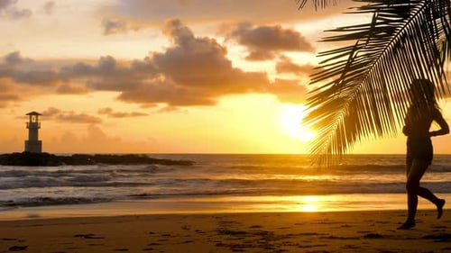 Woman Runs on Beach at Sunset with Lighthouse