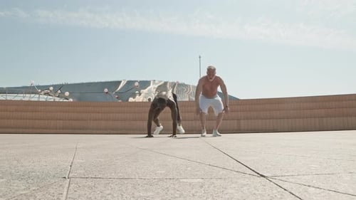 Homme âgé faisant des burpees avec un entraîneur de fitness personnel en plein air