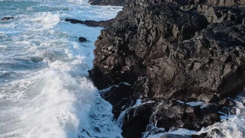 Experience the Stunning and Captivating Aerial View of Waves Crashing on the Rocky Shoreline