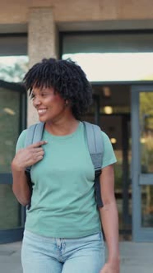 Young student walking and smiling outside university