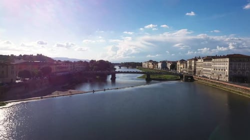 Aerial view flying fast above Arno River and city on a sunny day in Florence in Italy in 4k.