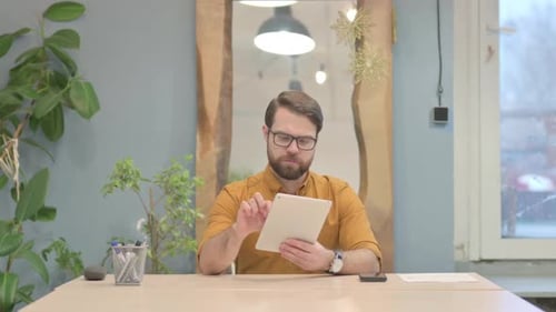 Man Works On Tablet at Office Desk