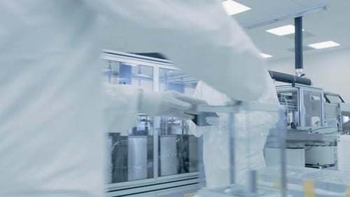 Quality Control Check: Scientist Using Digital Tablet Computer and wearing Protective Suit walks th