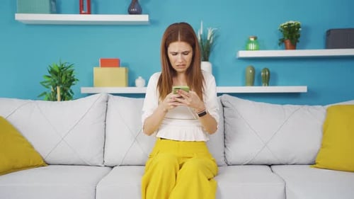 Woman on Couch Reacts with Distress to Smartphone