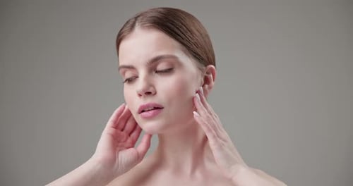 Elegant Woman Gently Touching Her Face and Neck
