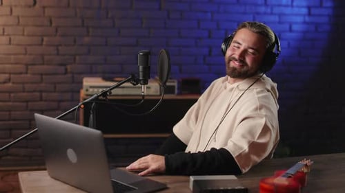 Musician in Headphones Using Laptop on Recording Studio
