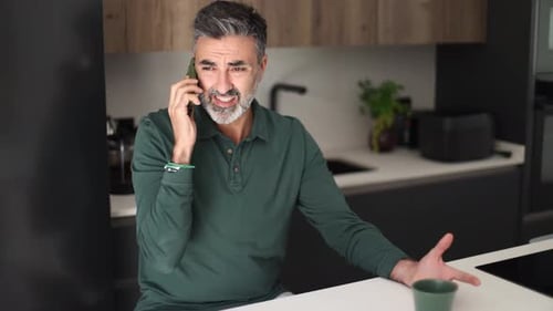 Upset Man Talking on Phone in Modern Kitchen