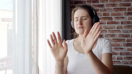 Woman Enjoys Music with Headphones, Dancing and Conducting