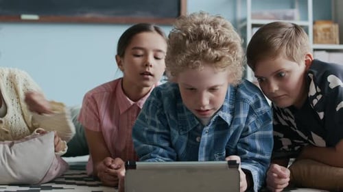Multiethnic Schoolchildren Looking at Digital Tablet and Chatting in Class