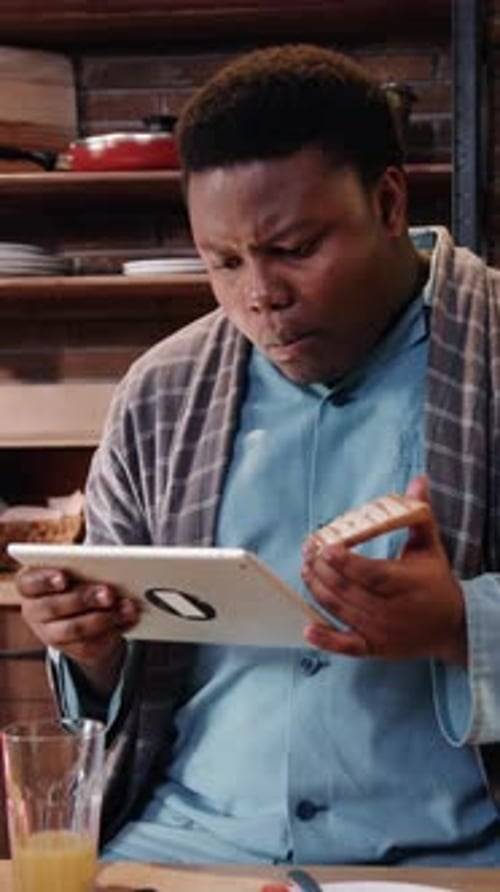 Man in Pajamas Using Tablet at Breakfast Table