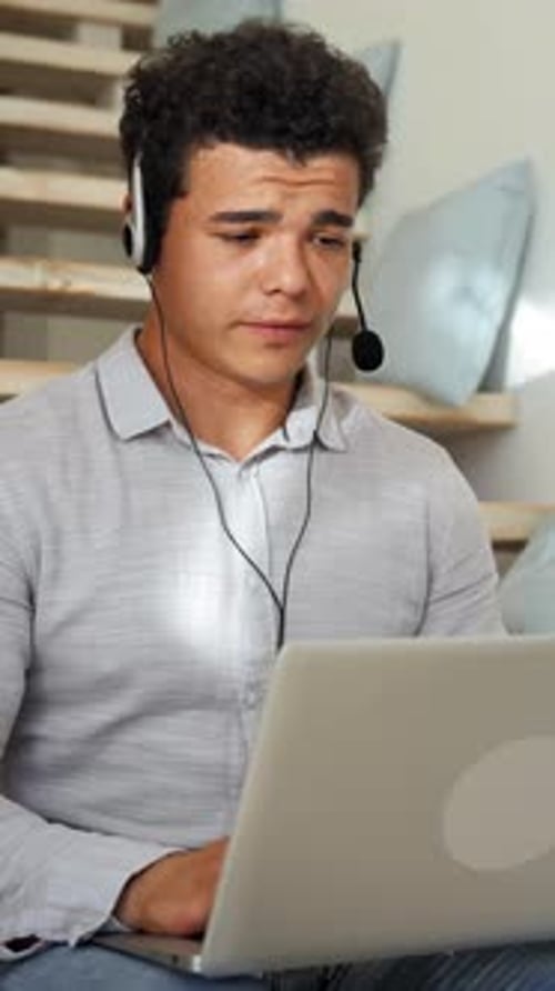 Young Adult Uses Laptop and Headset on Stairs