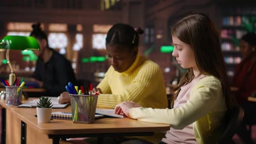 Teen Girls Reading Books in the Library to Focus on Mandatory Literature