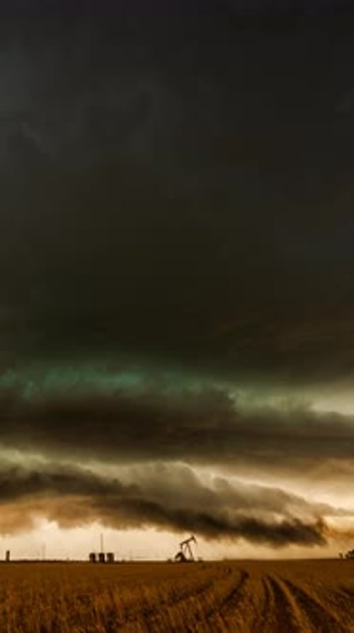 Stormy Sunset over Rural Field with Oil Derrick