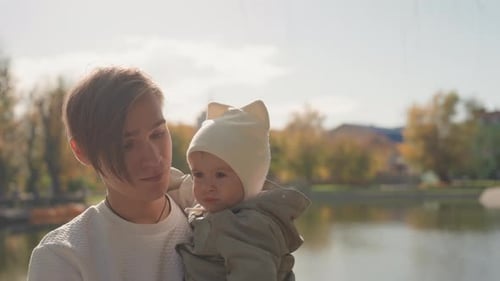Young Adult Holds Infant in a Park on Sunny Day