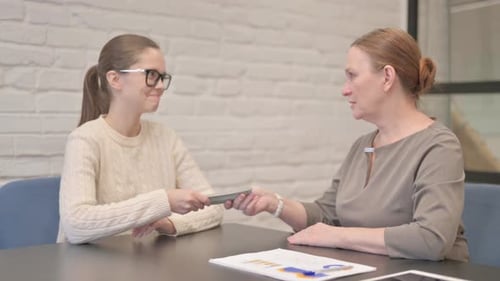 Senior Woman Giving Money to Young Woman