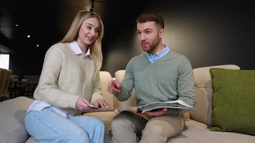 Young Couple Choosing New Furniture with Catalog for New Modern Home
