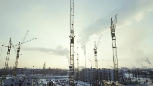 Sitio de construcción con grúas bajo un cielo nublado durante el invierno en una zona urbana