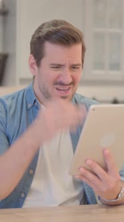 Young Man Upset by Loss on Tablet, vertical video