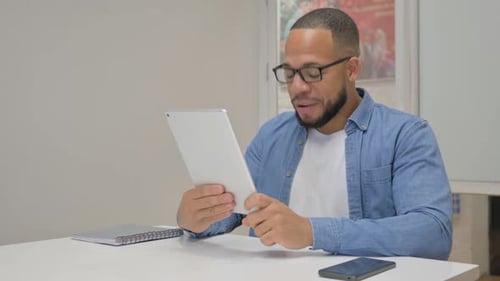 African Businessman Doing Video Chat on Tablet in Office
