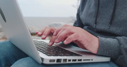 Jovem freelancer trabalha em um laptop na natureza nas montanhas