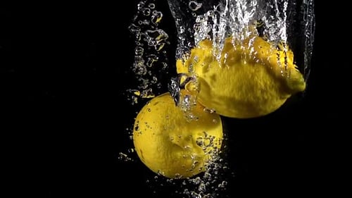 Lemons Falling Into Water Creating Bubbles and Splashes