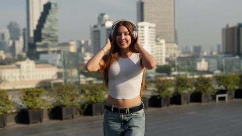 Portrait of Happy Woman Listens to Music Walking Along Urban Embankment