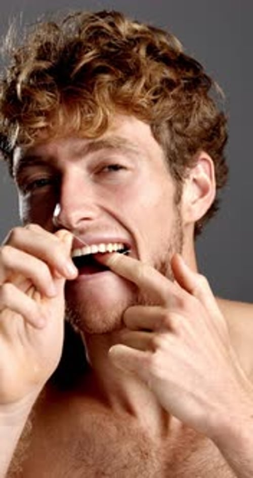 Man, face and floss in studio for dental care, hygiene and grooming for teeth whitening with smile